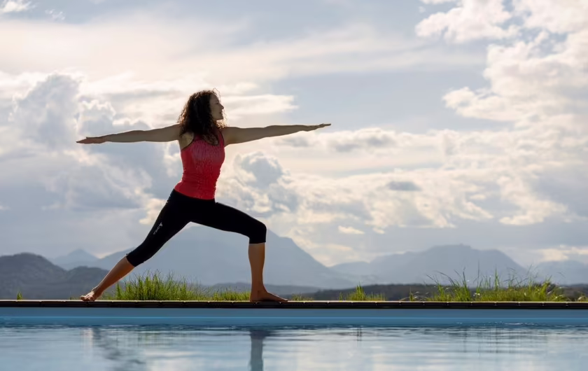 Frau macht eine Yogafigur am Outdoor Poolrand