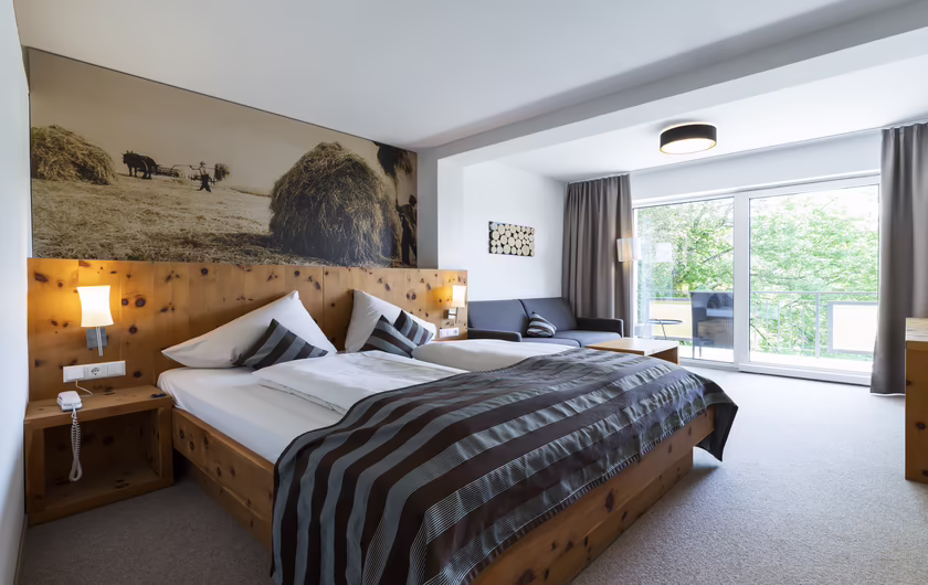 großes Doppelbett mit Holz und einem Bild inkl. Sitzecke und großen Fenstern