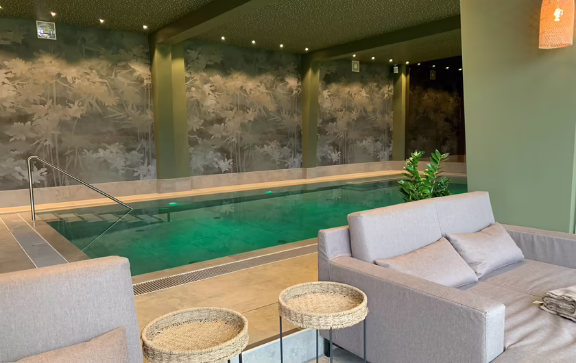 großer Indoor Pool mit grauen Liegen und entspannter Atmosphäre 