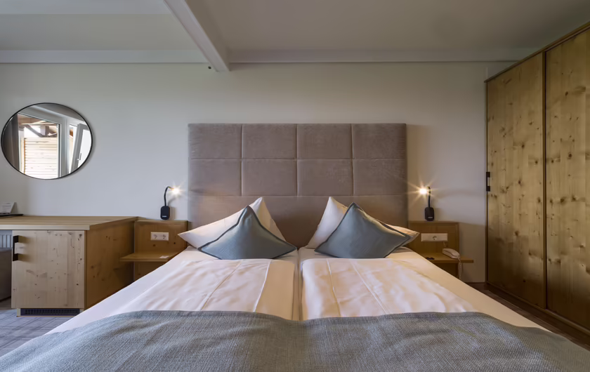 großes Doppelbett mit blau / grauer Bettdecke und hohem Kopfstück