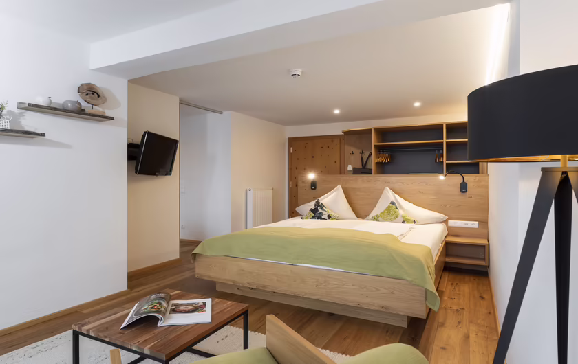 großes Zimmer mit einem Doppelbett, Schrank aus Holz, TV und Sitzecke