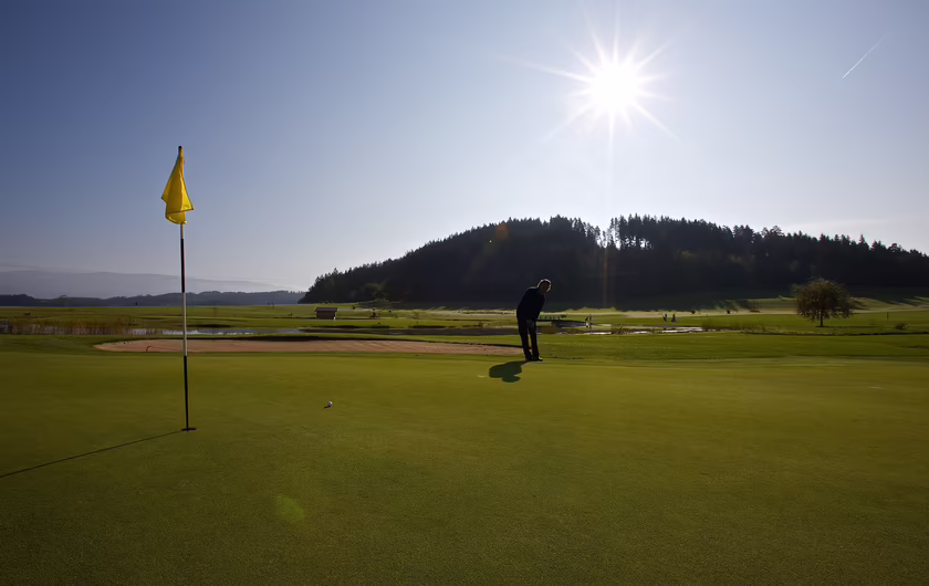 Ein Mann ist bei Sonnenschein am Golfen